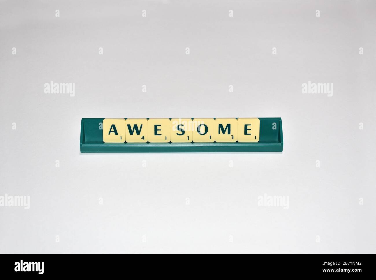 Scrabble tiles spell out Awesome. Motivational quote Scrabble Blocks Letters Grey Background Life quote Induce Alphabet. Stock Photo