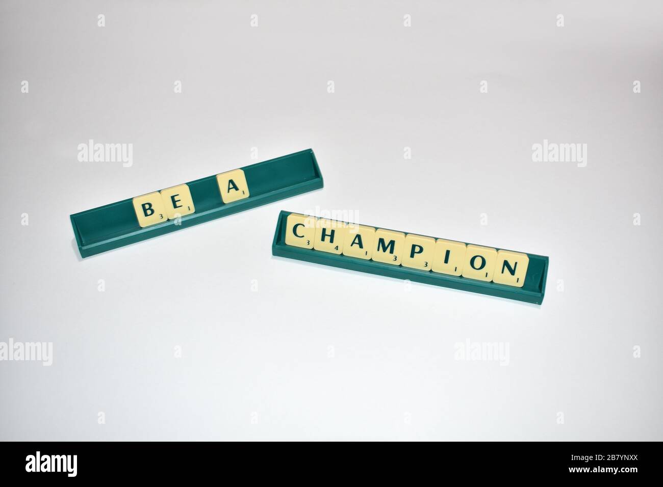 Scrabble tiles spell out Be a Champion. Motivational quote Scrabble Blocks Letters Grey Background Life quote Induce Alphabet. Stock Photo