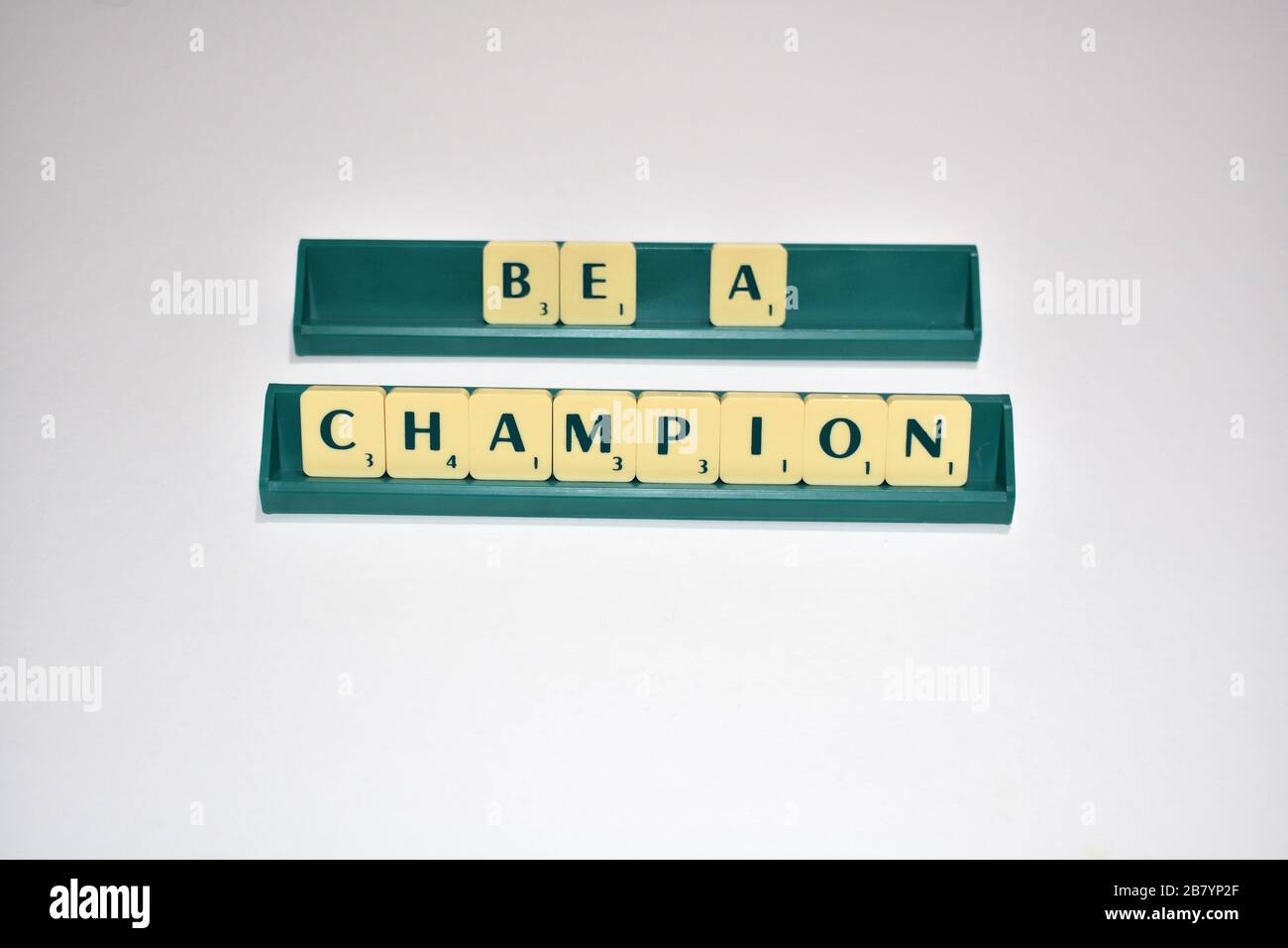 Scrabble tiles spell out Be a Champion. Motivational quote Scrabble Blocks Letters Grey Background Life quote Induce Alphabet. Stock Photo