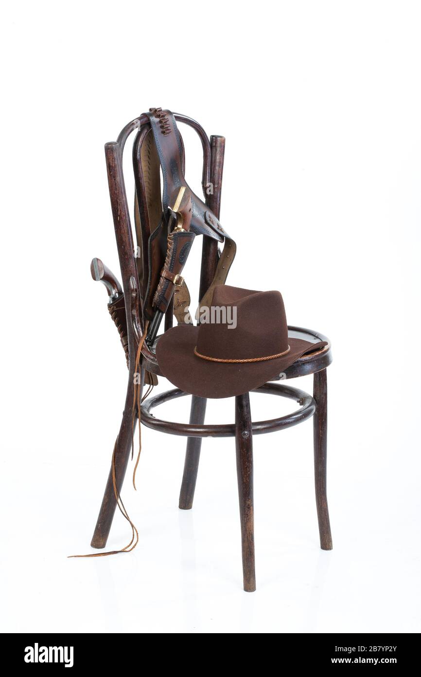 Cowboy belt, guns and hat on an old chair on isolated background Stock Photo