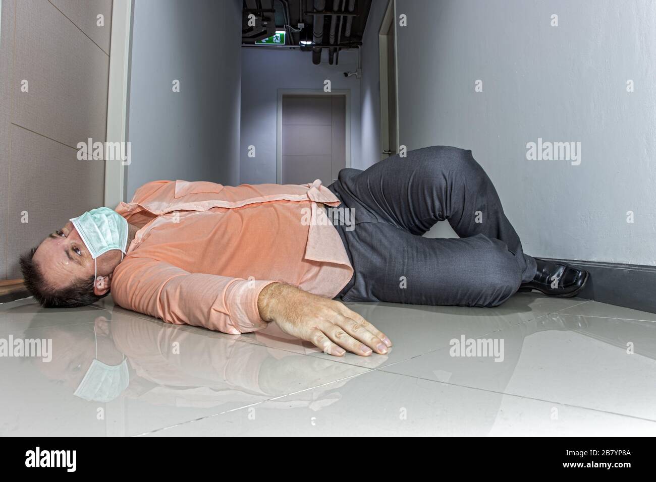 A Man With Protective Mask On Face Lying On Floor At Corridor Of