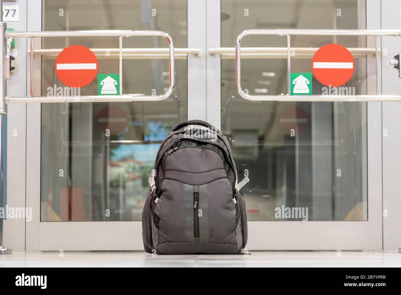 Backpack standing in front of closed door of departure gate at airport terminal. A lonely baggage at the airport. Stock Photo