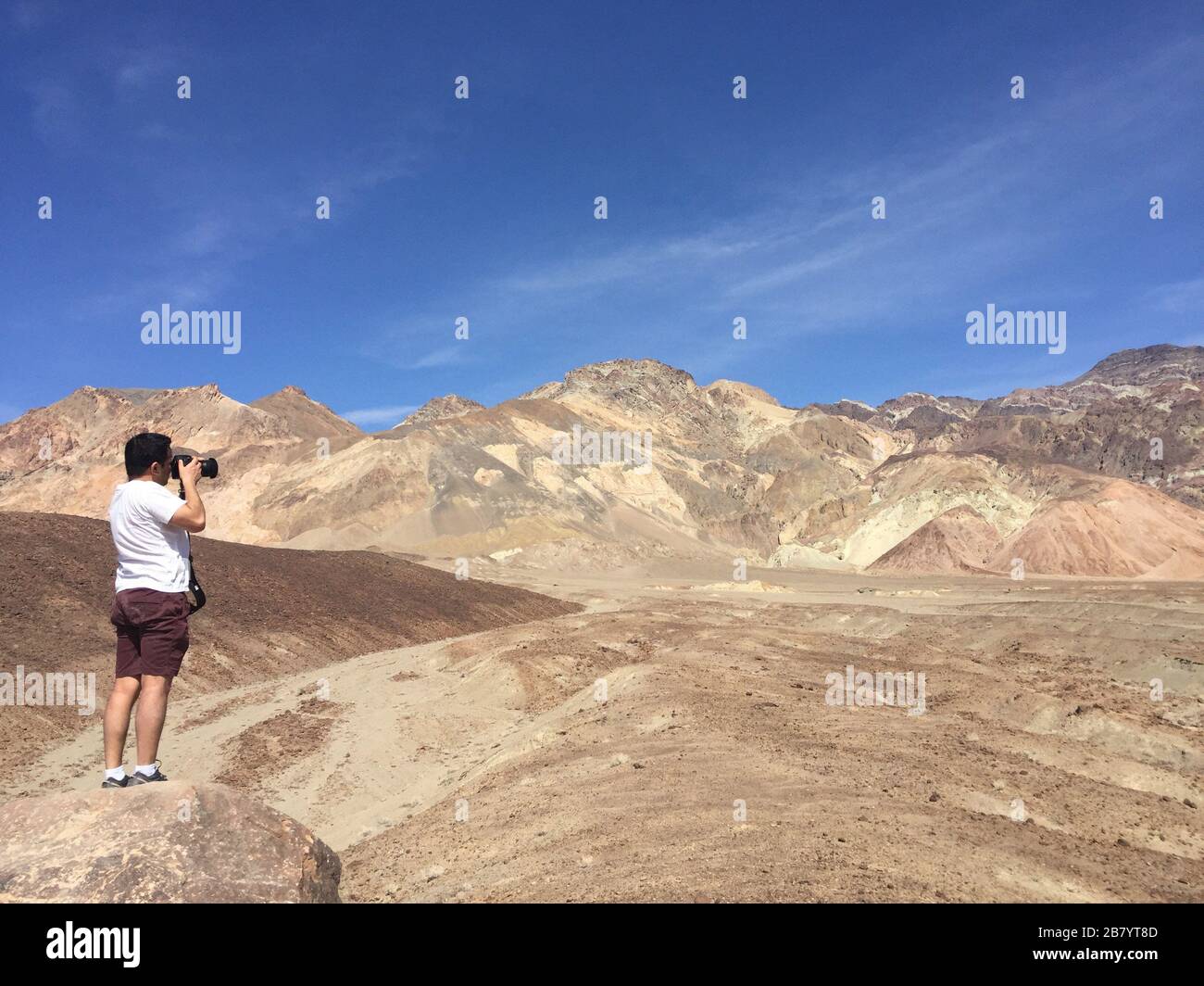 Man taking photograph of Artists palette at Death Valley National Park in California USA Stock Photo