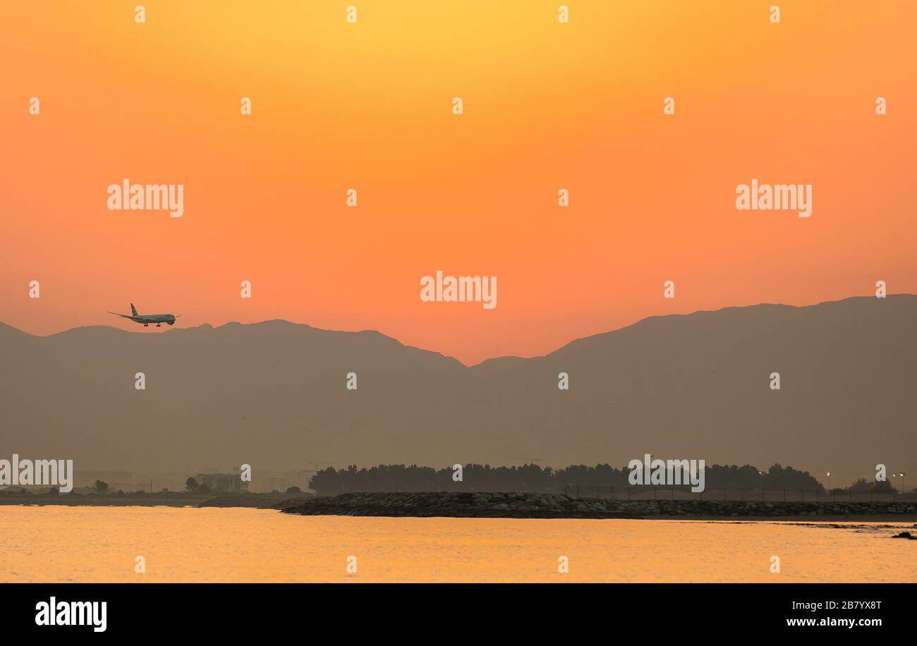 A flight flying during sunrise over a beach and alongside mountains Stock Photo