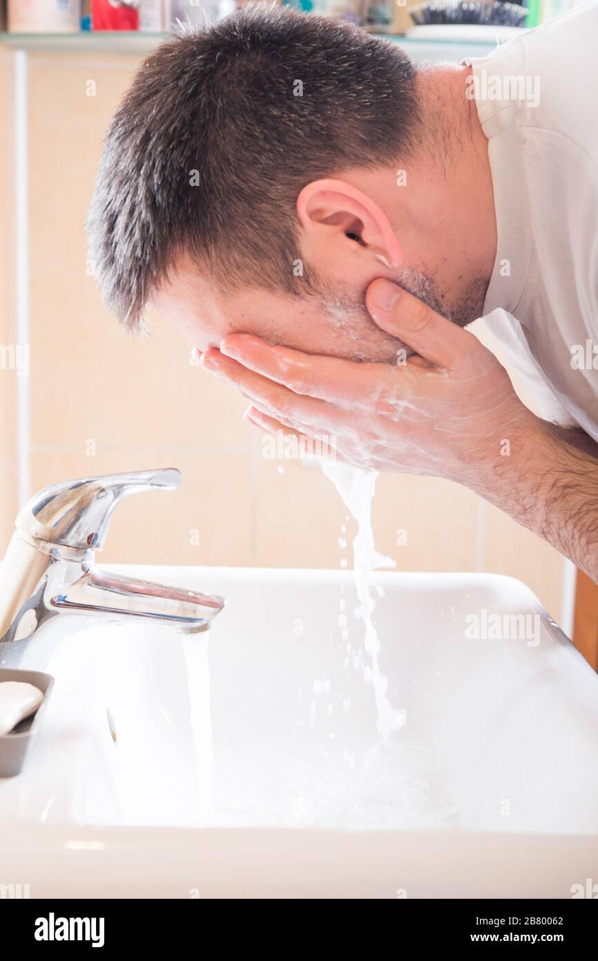 Man Washing Face In Bathroom Sink Stock Photo