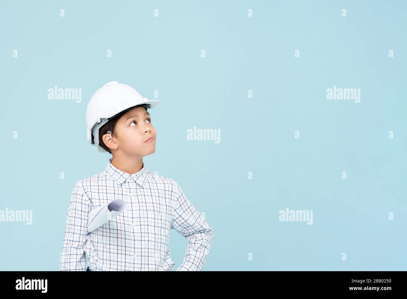 Doubt engineer boy with white helmet looking upward isolated on light blue background Stock Photo