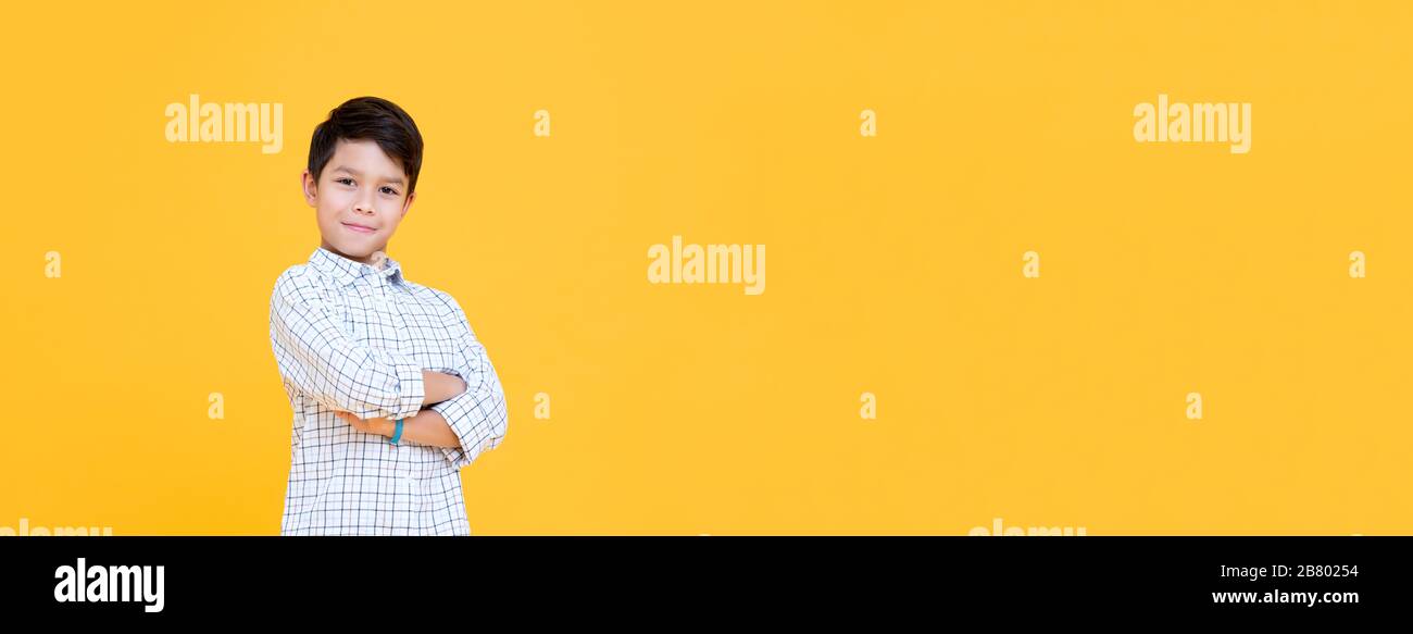 Happy smiling boy with arm crossed gesture isolated on yellow banner background with copy space Stock Photo