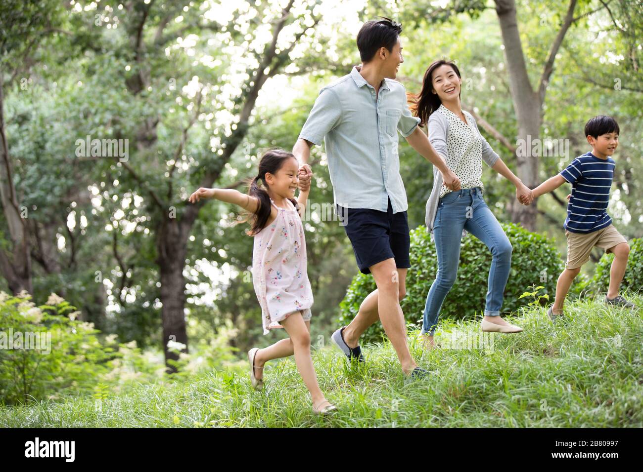 Happy young Chinese family running on grass Stock Photo - Alamy