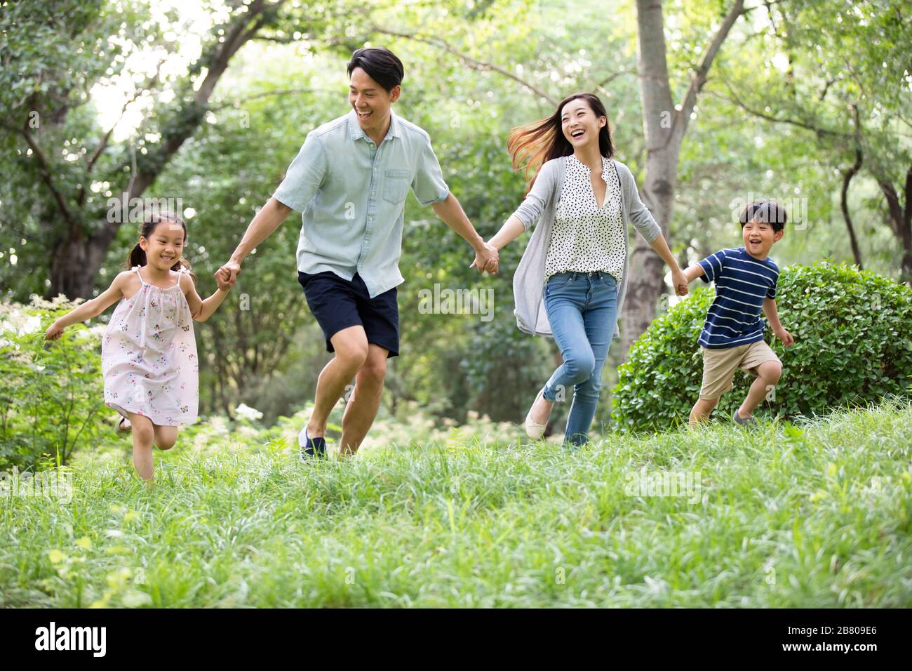 Happy young Chinese family running on grass Stock Photo - Alamy