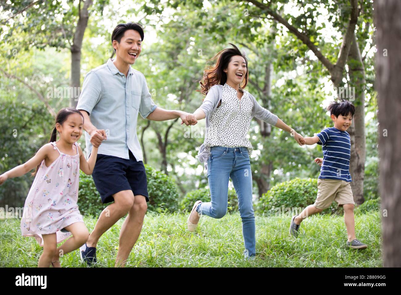 Happy young Chinese family running on grass Stock Photo - Alamy
