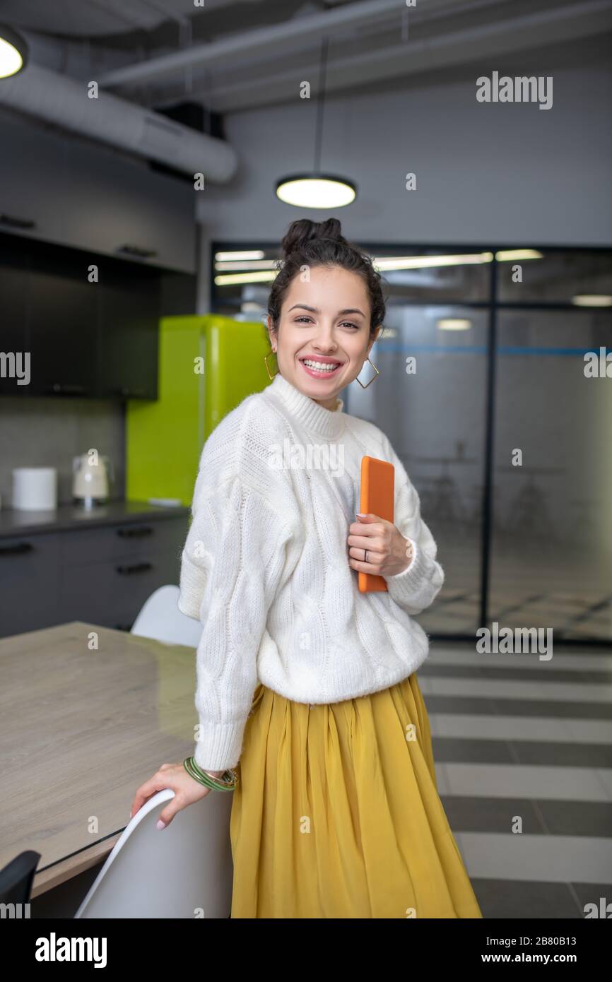 Young woman standing at the table, holding tight her tablet Stock Photo