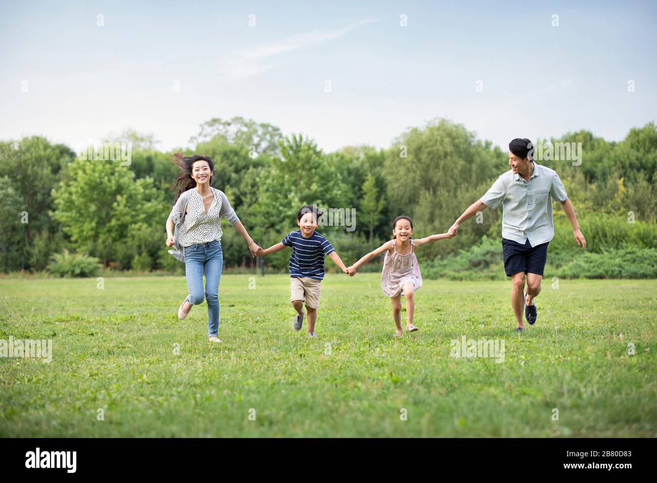 Happy young Chinese family running on grass Stock Photo - Alamy