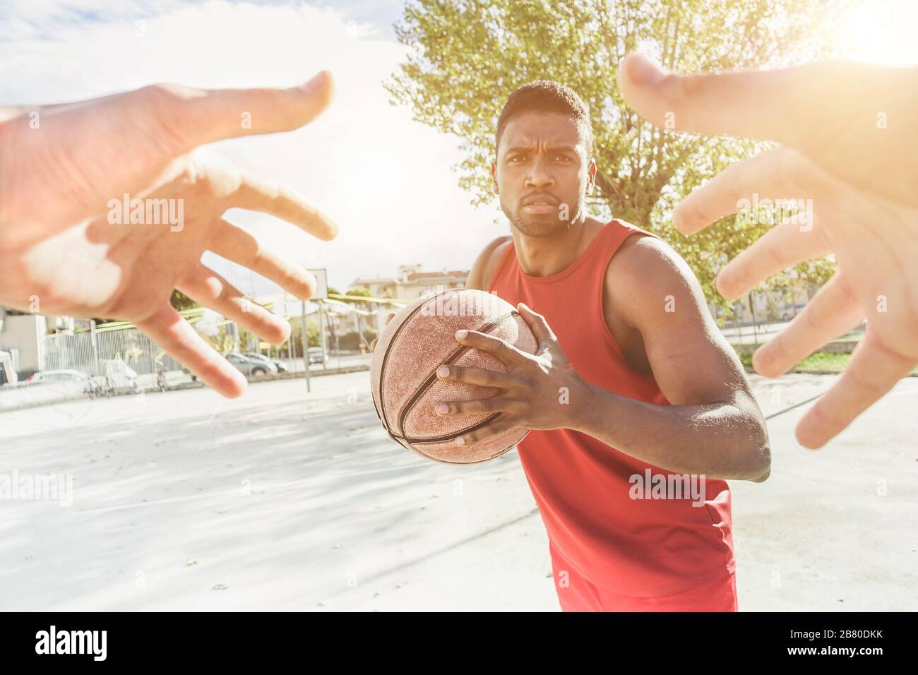 Multiracial basket player playing a game in urban quarter street camp outdoor with back lighting- Athlete hands trying to catch the ball from his oppo Stock Photo