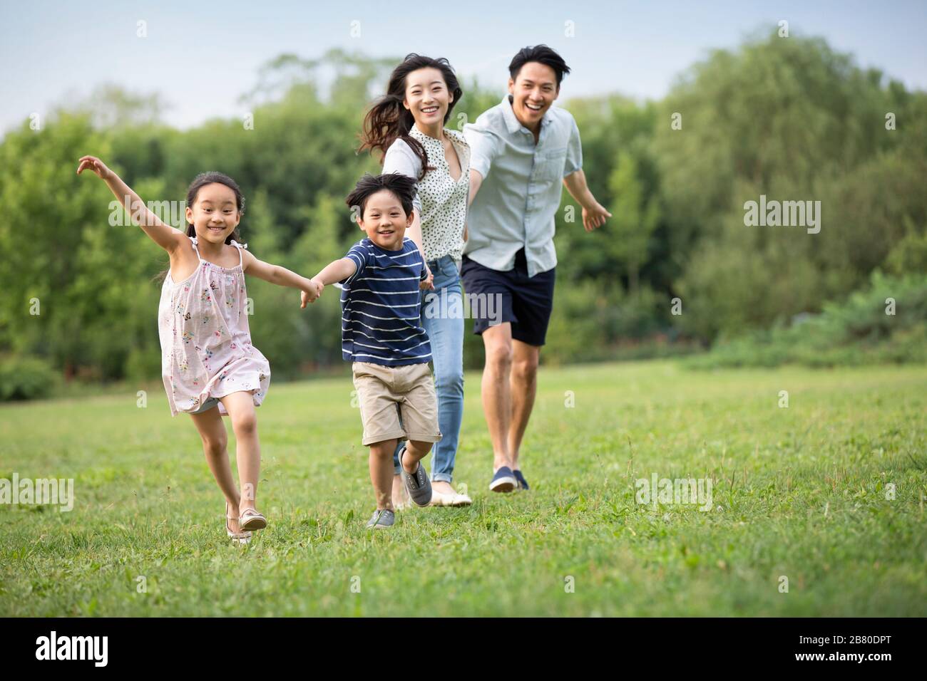 Happy young Chinese family running on grass Stock Photo - Alamy