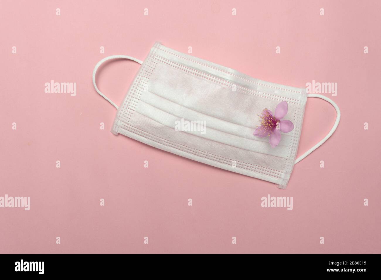 white health protective mask from corona virus or covid-19 disease with natural cute pink flower Stock Photo