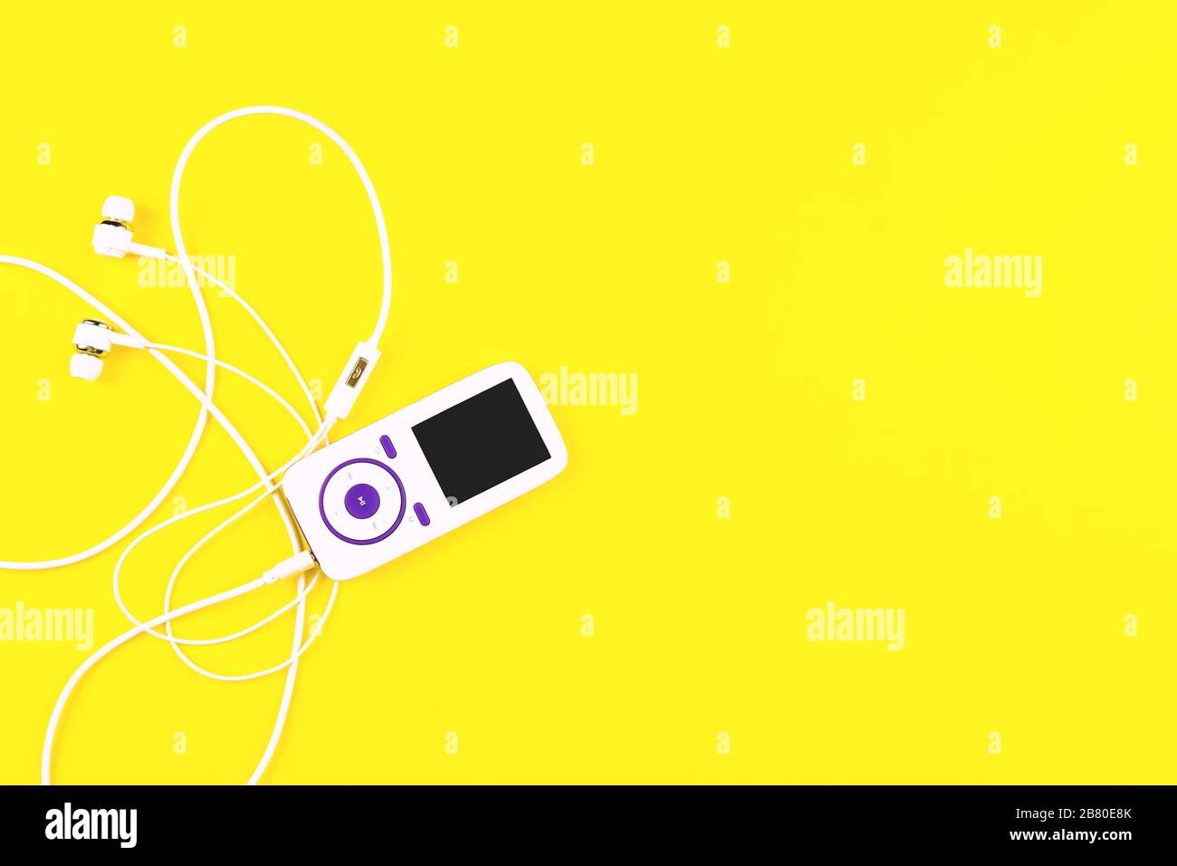 White music player with earphones on yellow background. Place for text, flat lay. Stock Photo
