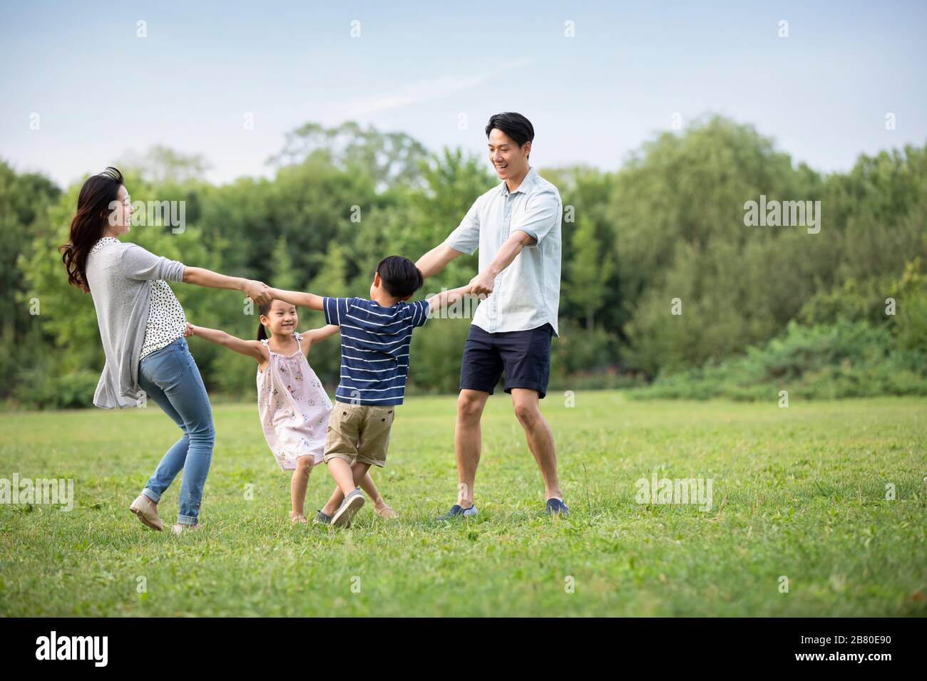 Happy young Chinese family playing on grass Stock Photo