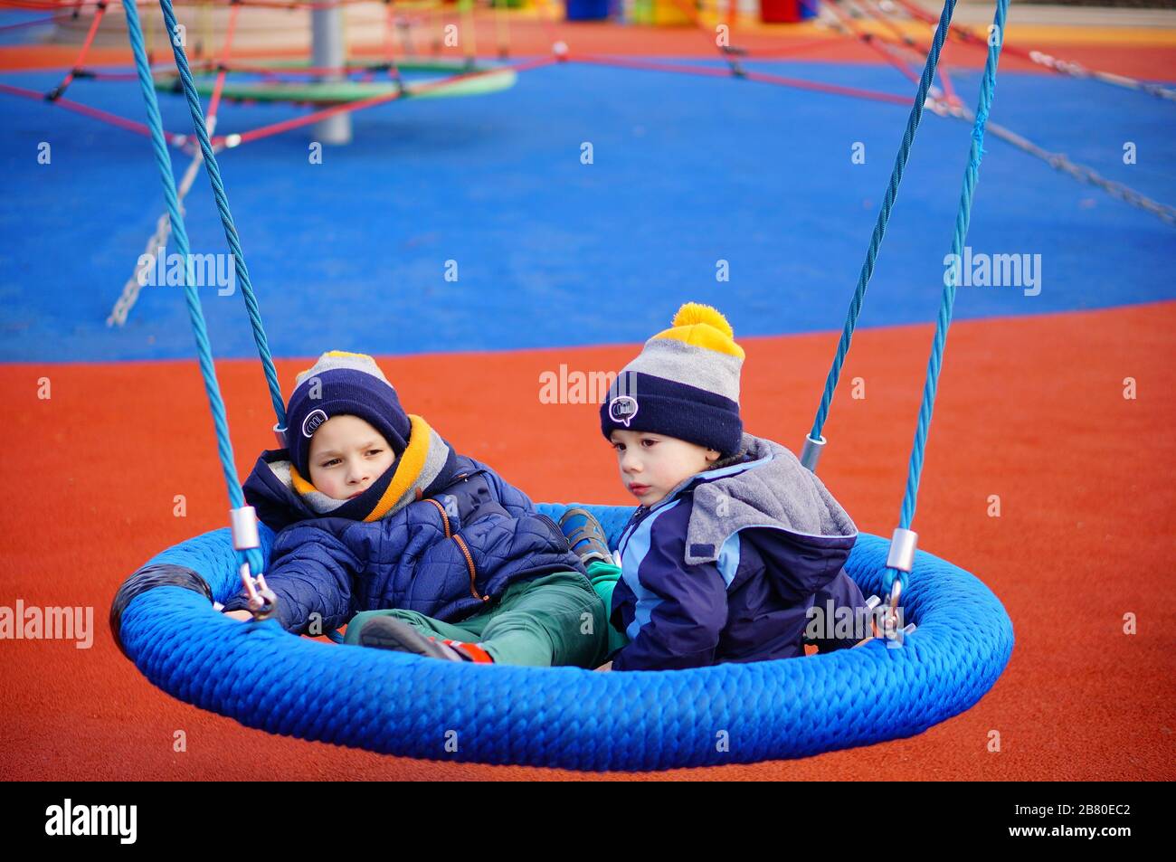 POZNAN, POLAND - Mar 08, 2020: Two young boys sitting on a net swing set equipment at a playground in the Rataje park. Stock Photo