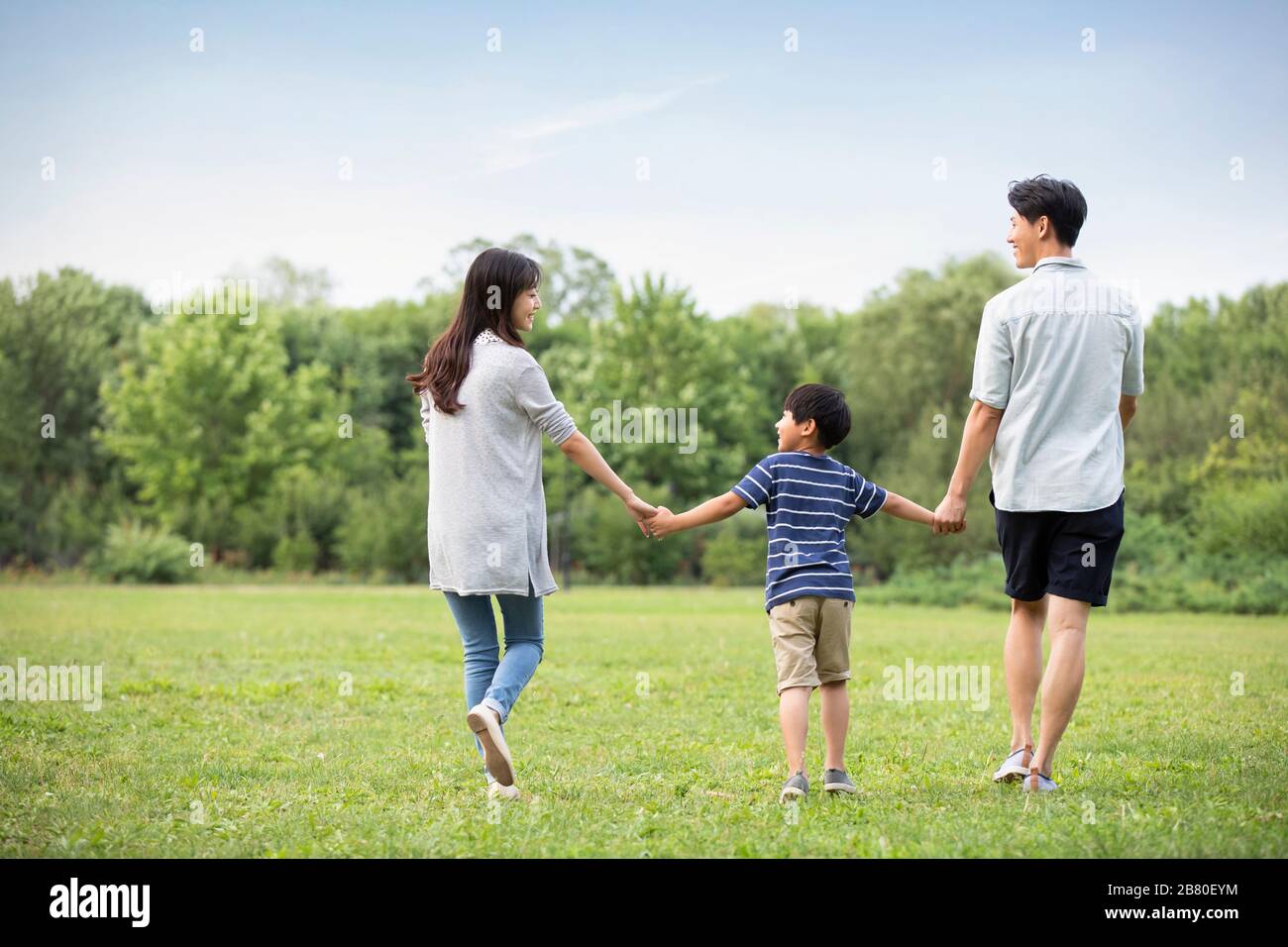 Happy young Chinese family walking on grass Stock Photo - Alamy