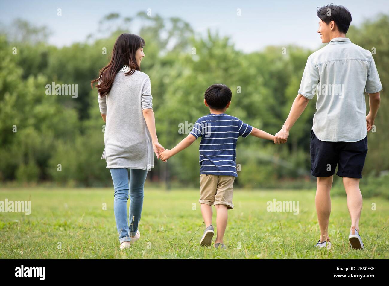 Happy young Chinese family walking on grass Stock Photo - Alamy