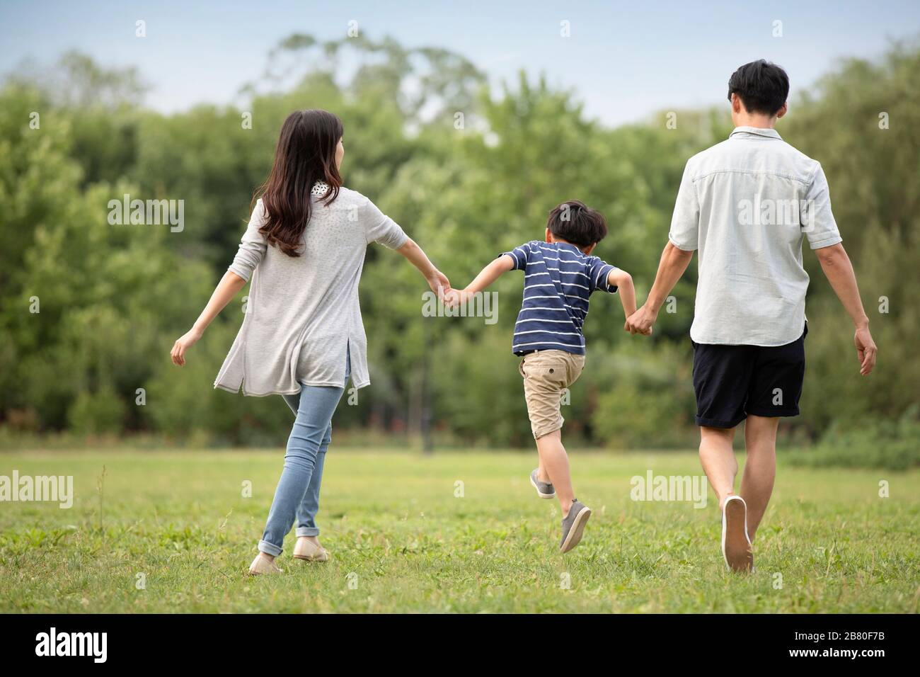 Happy young Chinese family walking on grass Stock Photo - Alamy