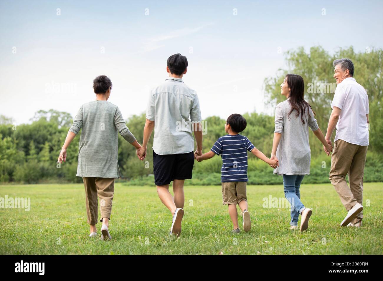 Happy Chinese family walking on grass Stock Photo - Alamy