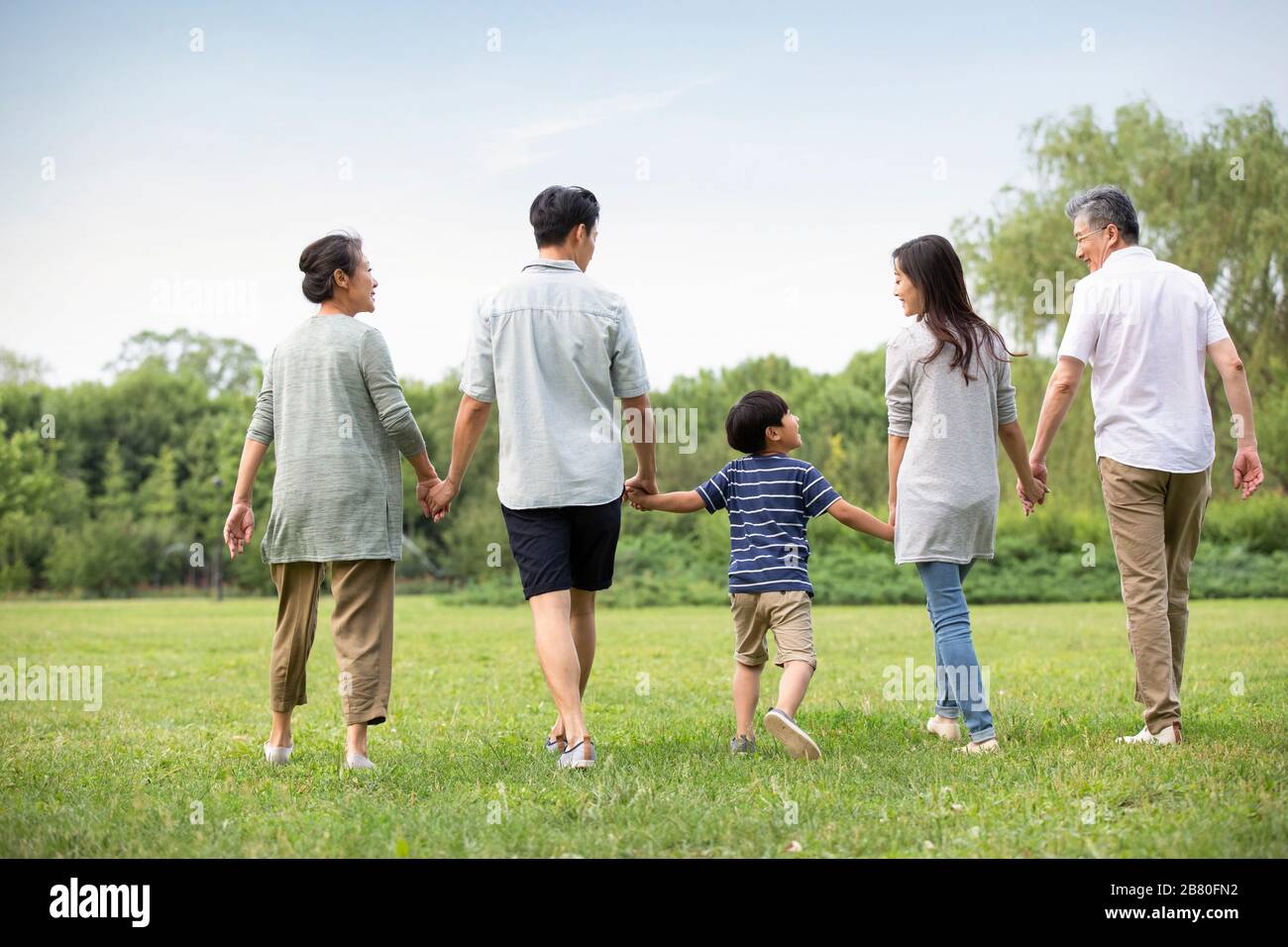 Happy Chinese family walking on grass Stock Photo - Alamy