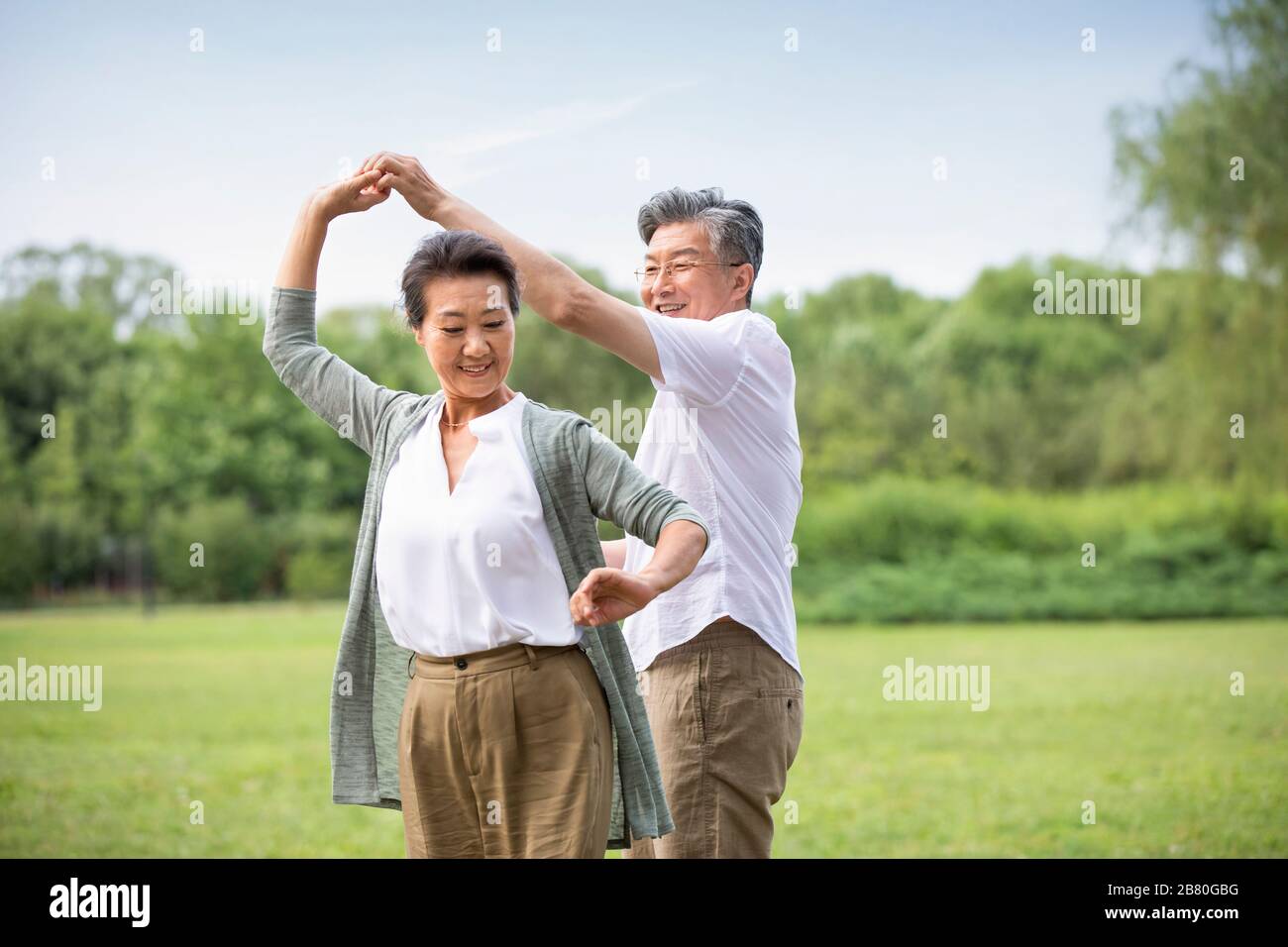Happy senior Chinese couple dancing on grass Stock Photo - Alamy