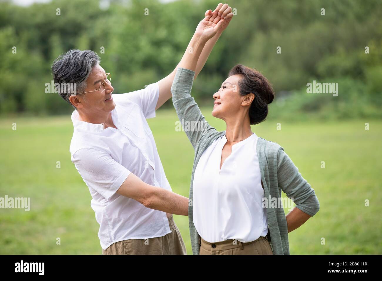 Happy senior Chinese couple dancing on grass Stock Photo - Alamy