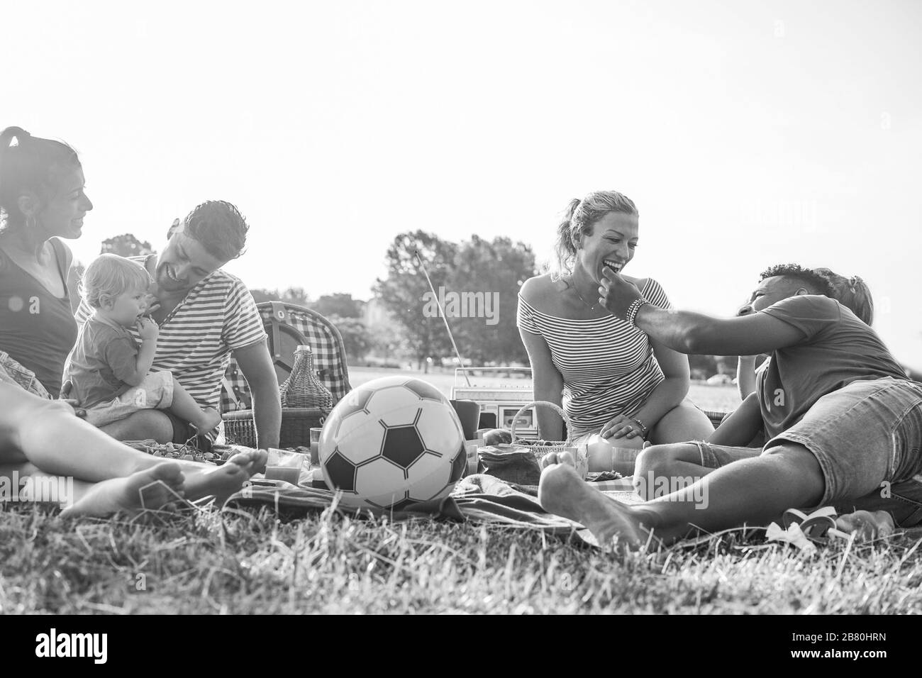 Happy families doing picnic in park outdoor - Young parents having fun with children in summer time eating and playing - Food, weekend lifestyle and f Stock Photo