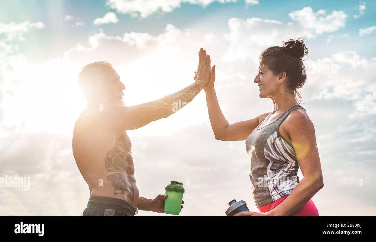 Couple of fitness friends athlete congratulating after workout sessions outdoor - Happy senior people training outside - Bodybuilding, empowering and Stock Photo