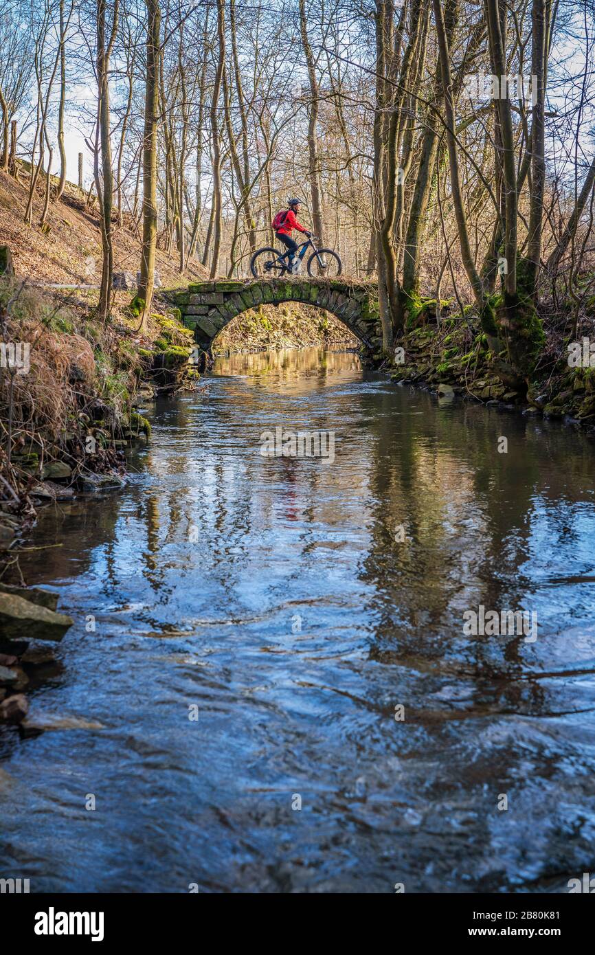 nice active senior woman riding her electric mountain bike in early spring along a little river near Stuttgart Stock Photo
