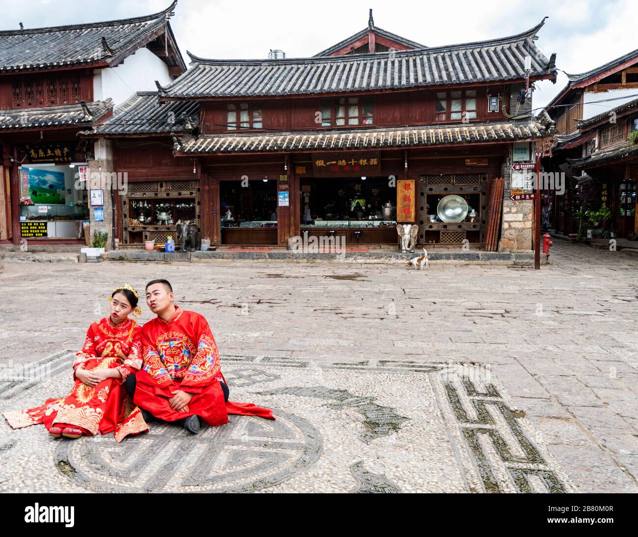 A newlywed couple wearing traditional costumes posing for wedding photos in the ancient town of Shuhe near Lijiang, Yunnan Province, China. Stock Photo