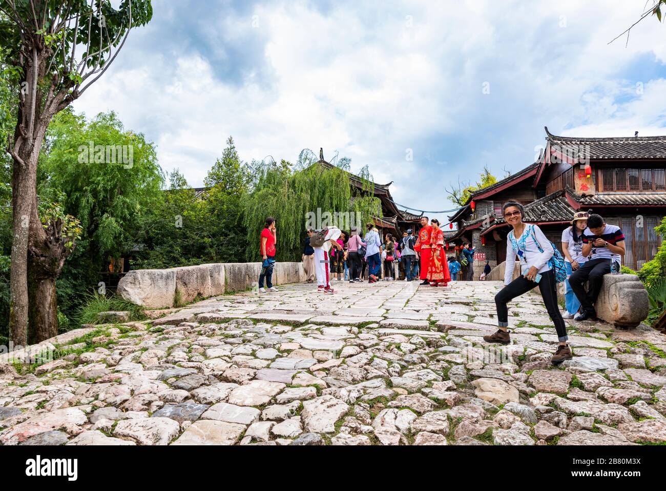 A newlywed couple wearing traditional costumes posing for wedding photos in the ancient town of Shuhe near Lijiang, Yunnan Province, China. Stock Photo