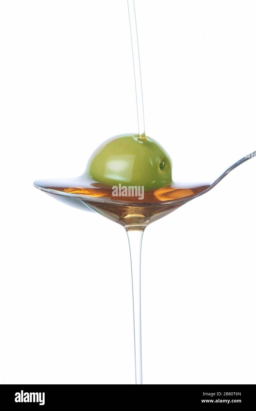 Olive on the spoon, pouring with oil Stock Photo Alamy