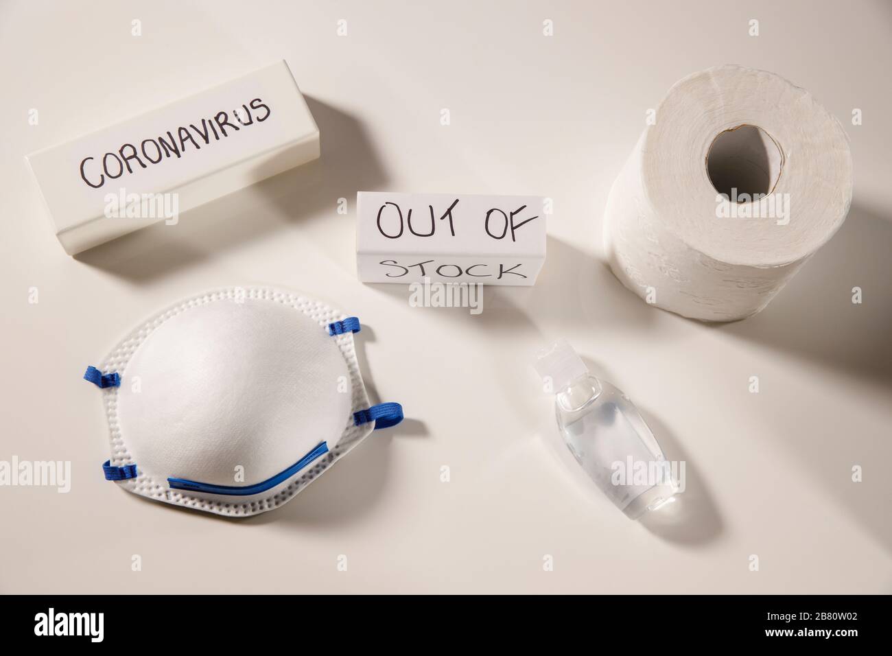 Coronavirus essentials out of stock concept,shortage personal masks, hand sanitizer and toilet paper, coronavirus text on white flay lay, top view Stock Photo