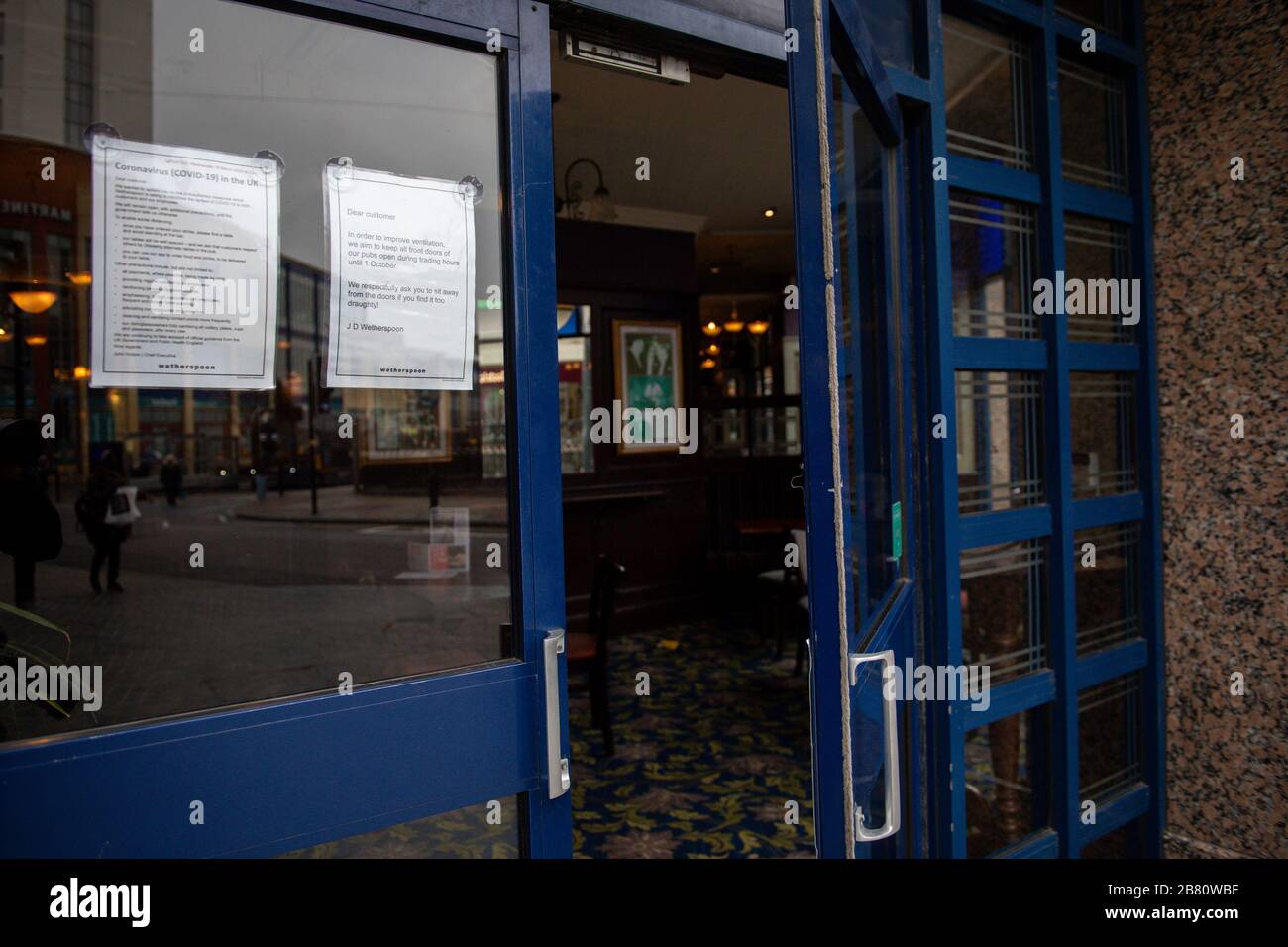 A sign on a JD Wetherspoon pub in Birmingham stating that to improve ventilation the doors will remain open. This on the day that emergency legislation to tackle the coronavirus outbreak will be published in Parliament after Prime Minister Boris Johnson announced the closure of schools and cancellation of exams. Stock Photo