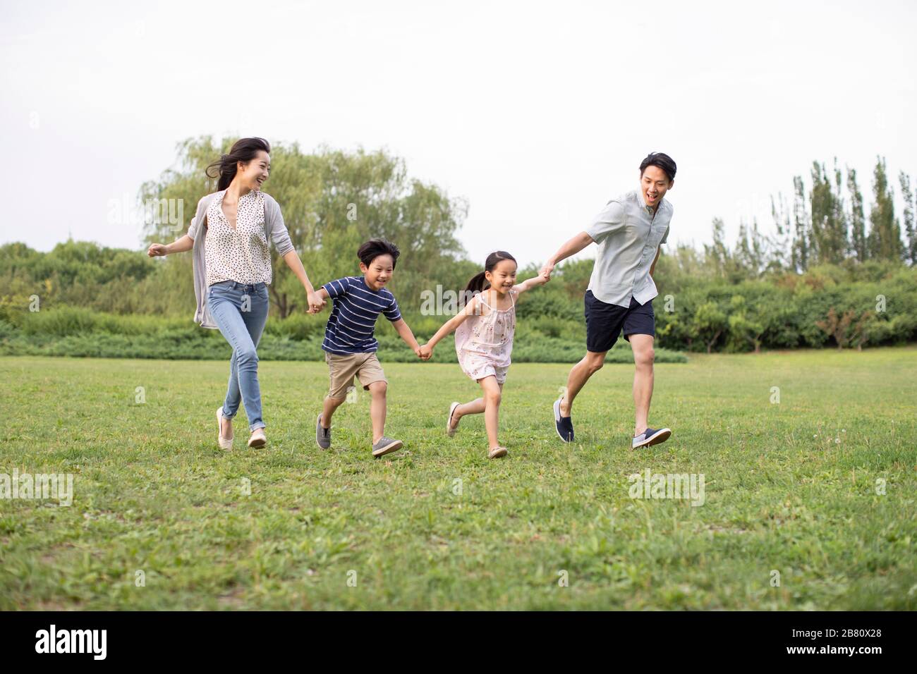 Happy young Chinese family running on grass Stock Photo - Alamy