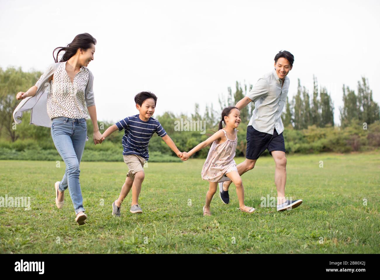 Happy young Chinese family running on grass Stock Photo - Alamy