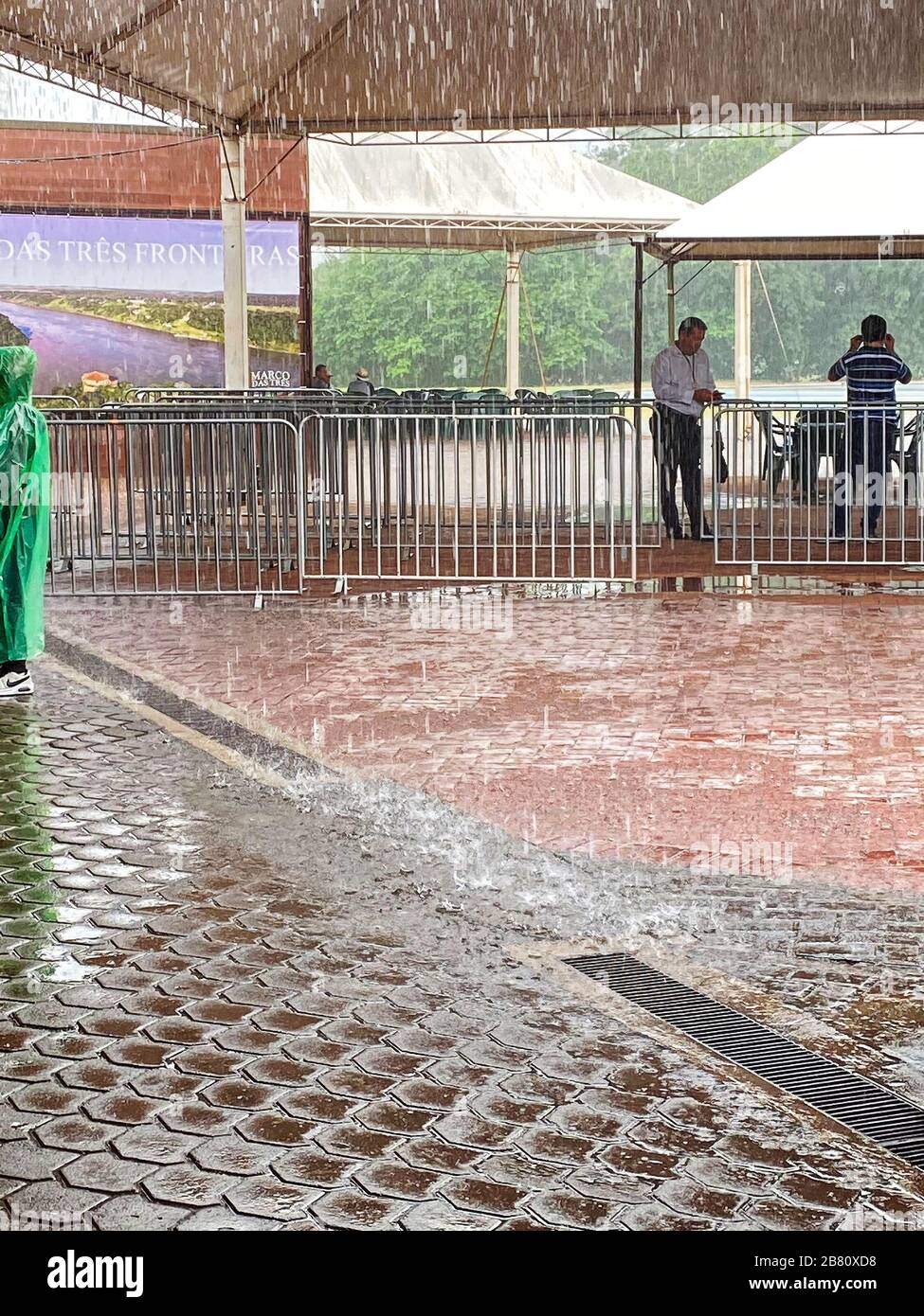 heavy rain, inclement weather, person wearing plastic slicker, men under cover, wet, drain, summer Stock Photo