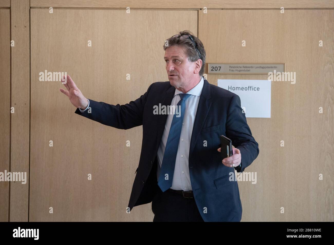 Stuttgart, Germany. 19th Mar, 2020. 19 March 2020, Baden-Wuerttemberg, Stuttgart: Manfred 'Manne' Lucha, Minister of Social Affairs of Baden-Württemberg, is standing in front of a plenary session of the state parliament of Baden-Württemberg in the foyer. The state parliament met for a special session to set the course for the fight against the coronavirus. During the session, the members of parliament should keep the recommended distance of 1.5 to 2 metres so that they do not infect each other in case a politician should be infected with the virus. Some Members should therefore take their seat Stock Photo