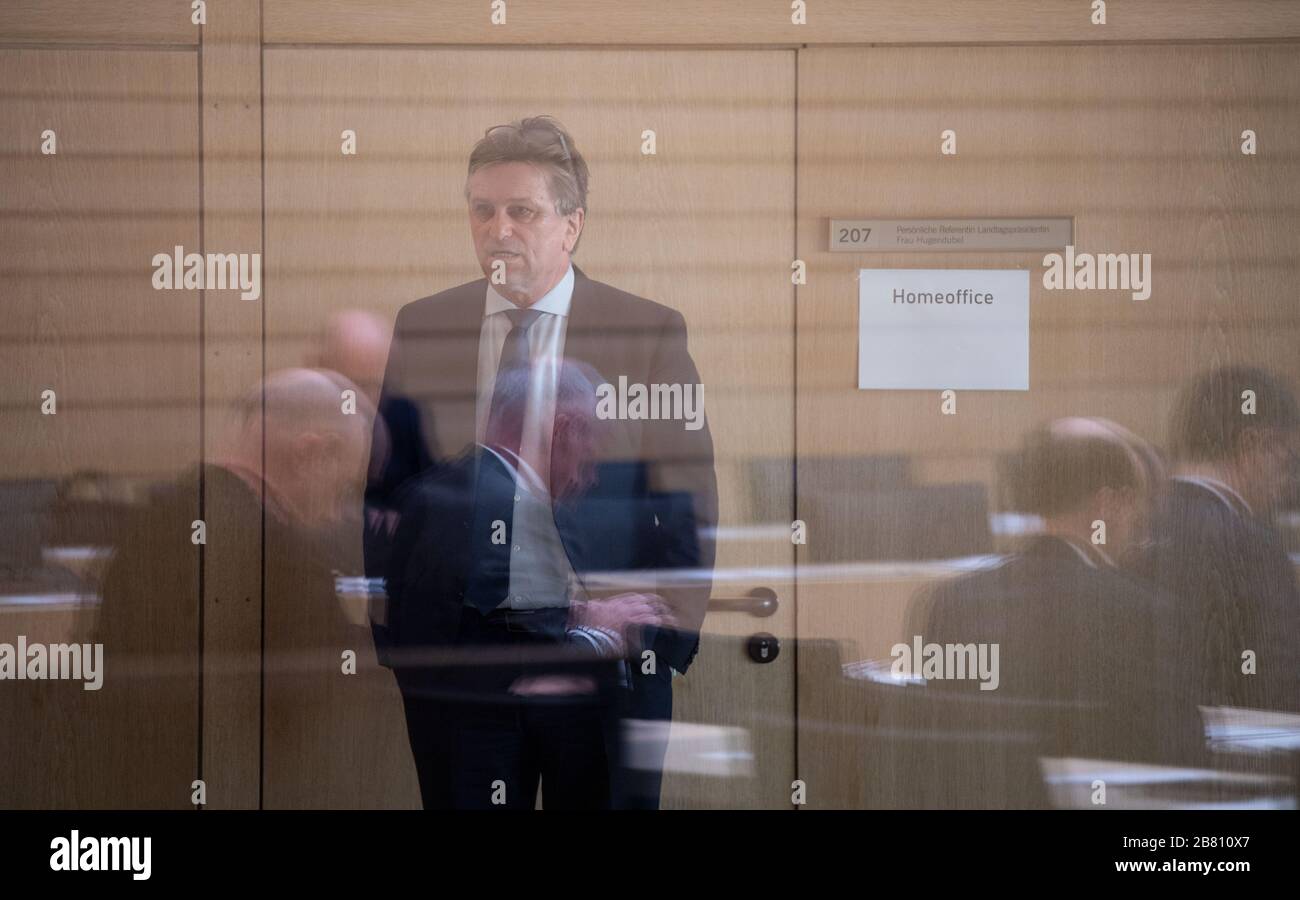 Stuttgart, Germany. 19th Mar, 2020. 19 March 2020, Baden-Wuerttemberg, Stuttgart: Manfred 'Manne' Lucha, Minister of Social Affairs of Baden-Württemberg, is standing behind a pane of glass in which members of parliament are reflected before a plenary session of the state parliament of Baden-Württemberg. The state parliament met for a special session to set the course for the fight against the coronavirus. During the session, the members of parliament should keep the recommended distance of 1.5 to 2 metres so that they do not infect each other in case a politician should be infected with the vi Stock Photo