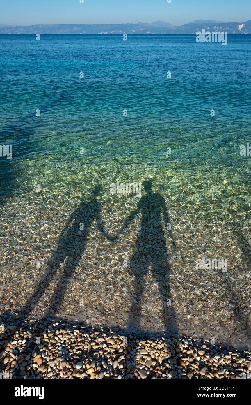 a loving couple on a beach creating shadows in the sea Stock Photo