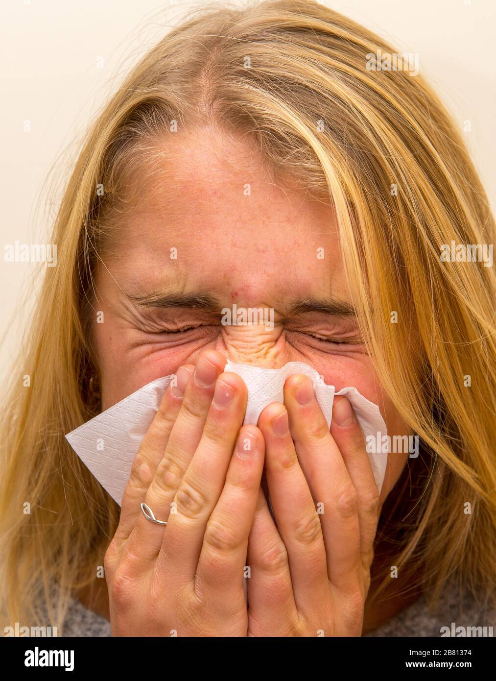 young woman sneezing her nose in a handkerchief Stock Photo