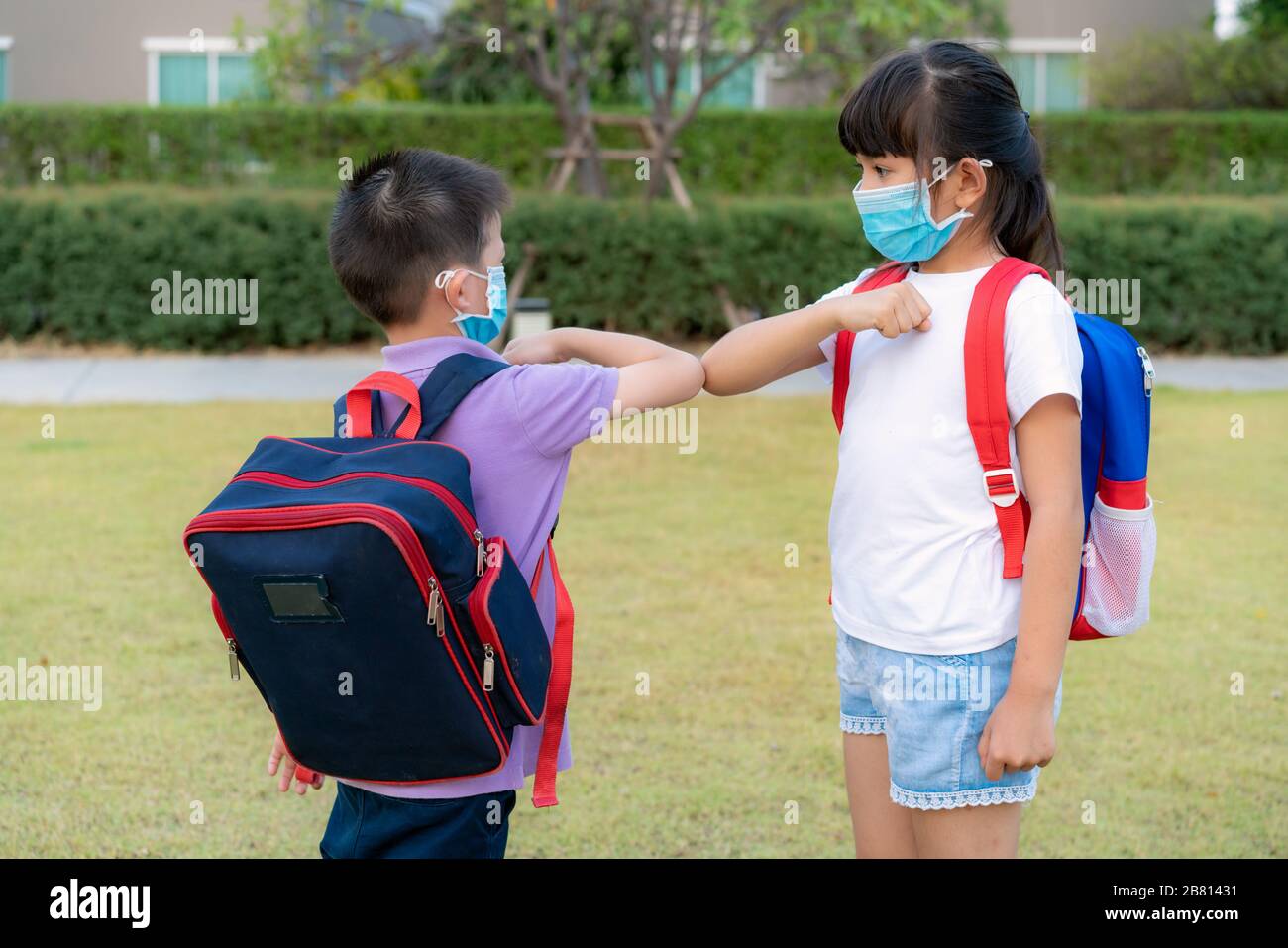 Elbow bump is new novel greeting to avoid the spread of coronavirus. Two Asian children preschool friends meet in  school park with bare hands. Instea Stock Photo