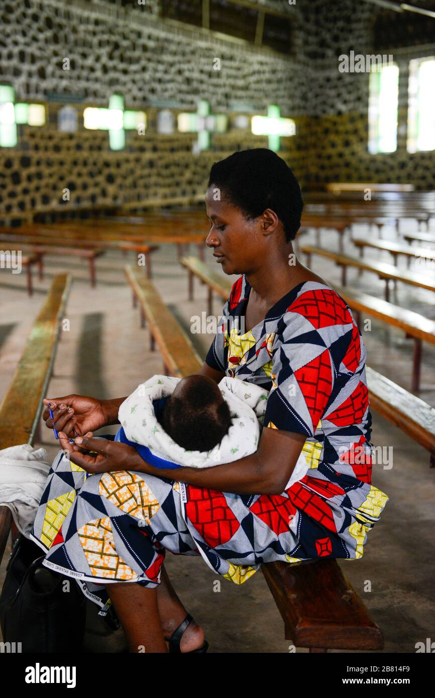 RWANDA, Ruhengeri, village Busogo, woman with baby praying a rosary in church / RUANDA, Frau mit Kleinkind in Kirche Busogo Stock Photo