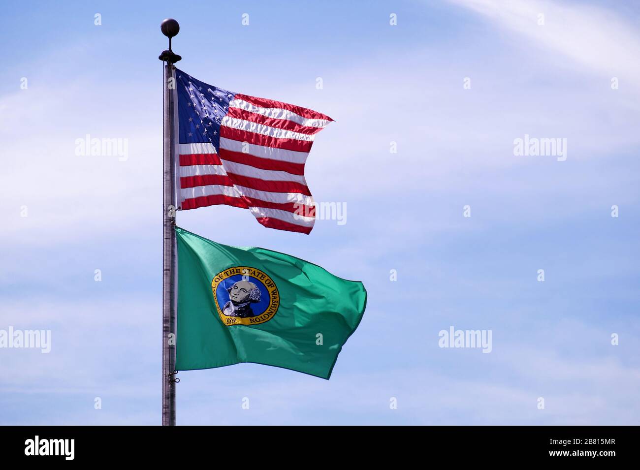 Against the sky. Flag of the United States of America and green flag of Washington - state flag. Stock Photo
