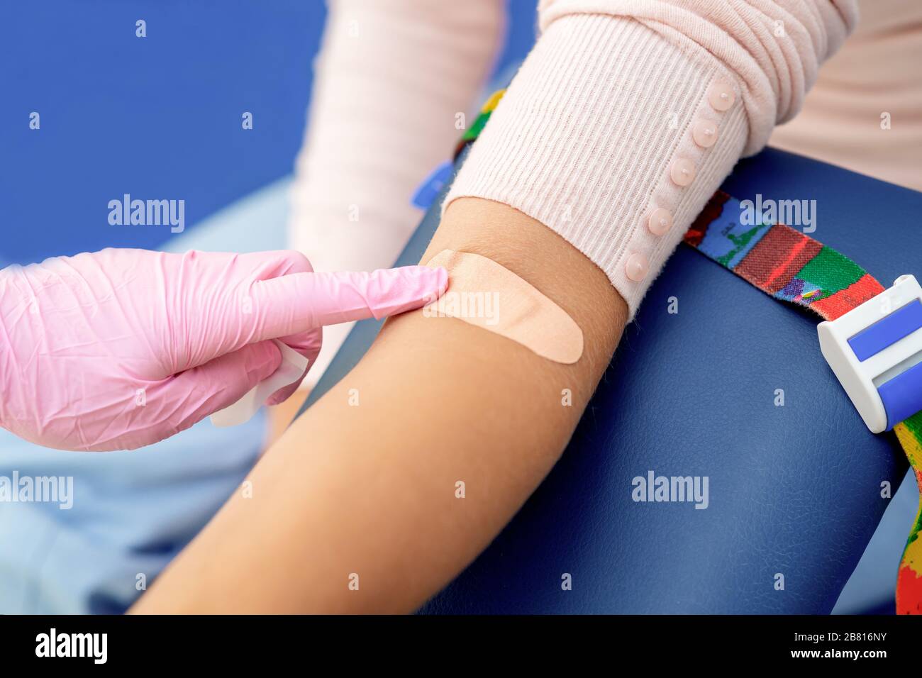 Doctor in rubber protective gloves glues an adhesive plaster on arm