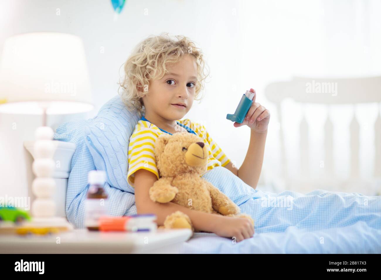 Sick little boy with asthma medicine. Ill child lying in bed. Unwell