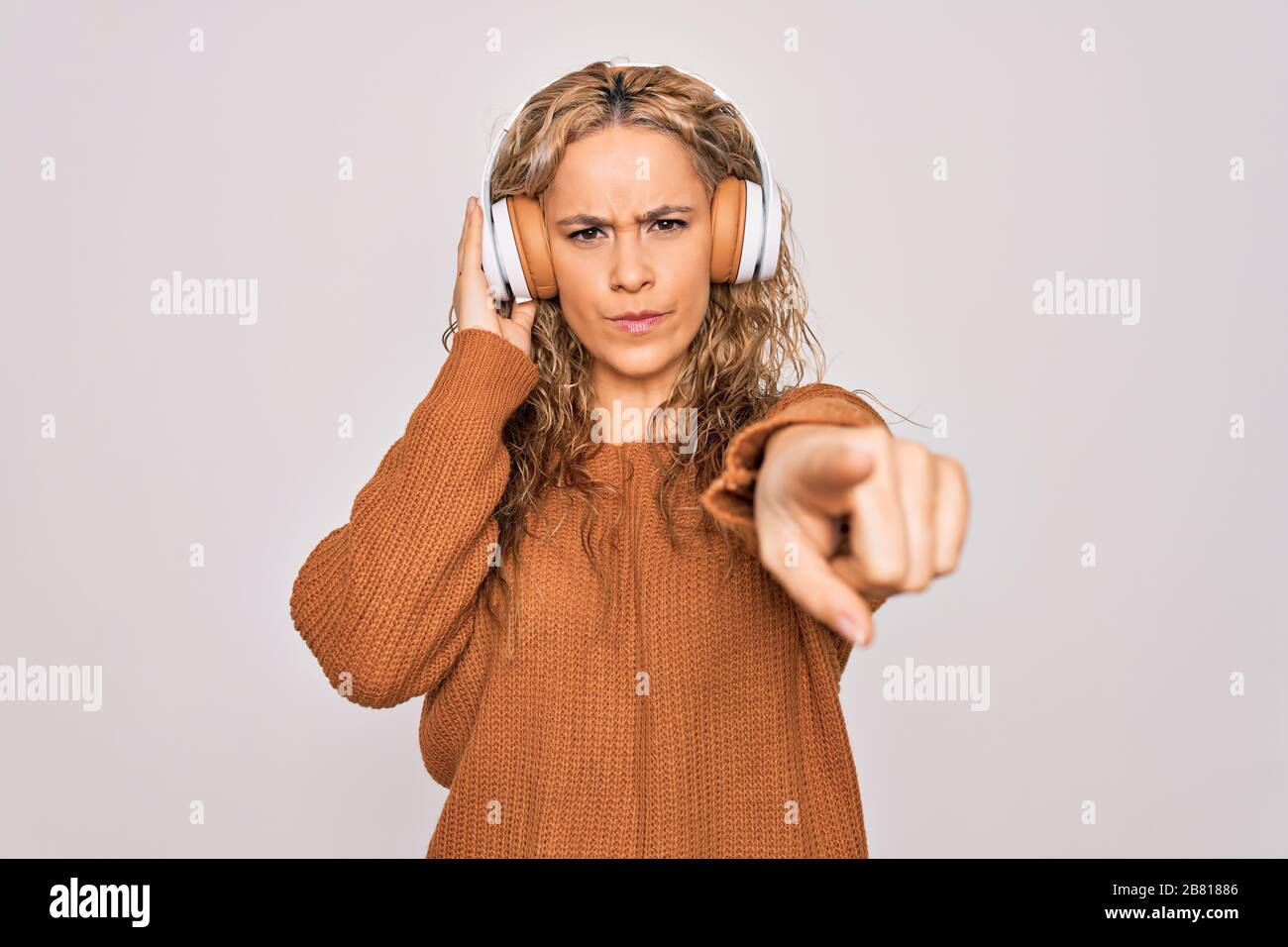 Young beautiful blonde woman listening to music using headphones over ...